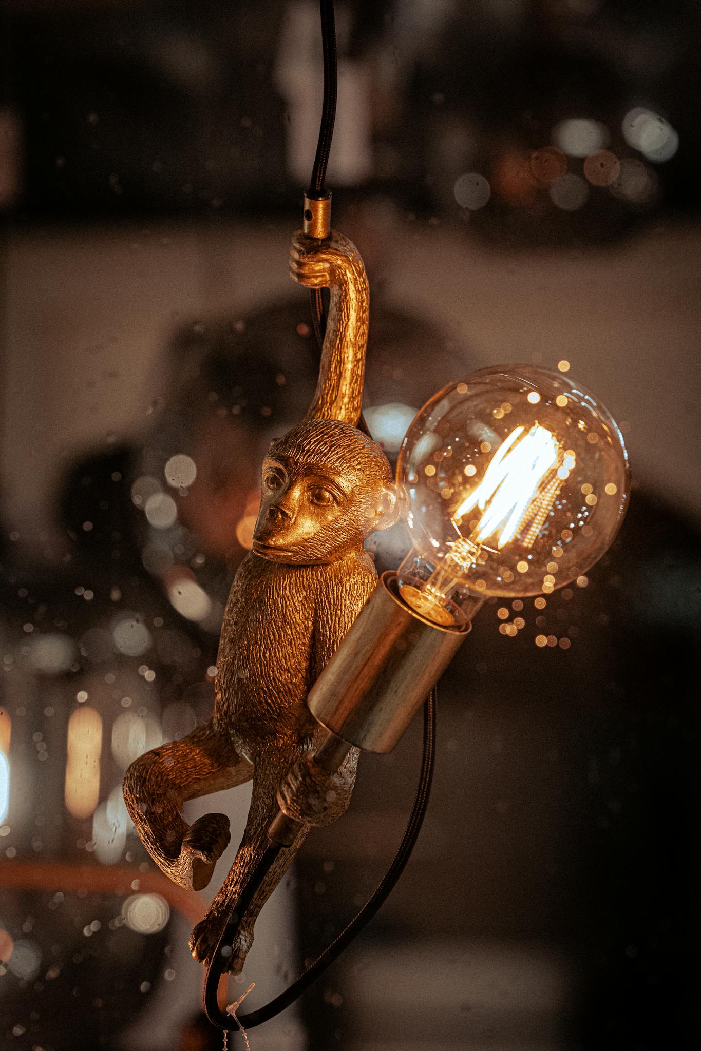 Close-up of a monkey figurine lamp with a glowing Edison bulb.